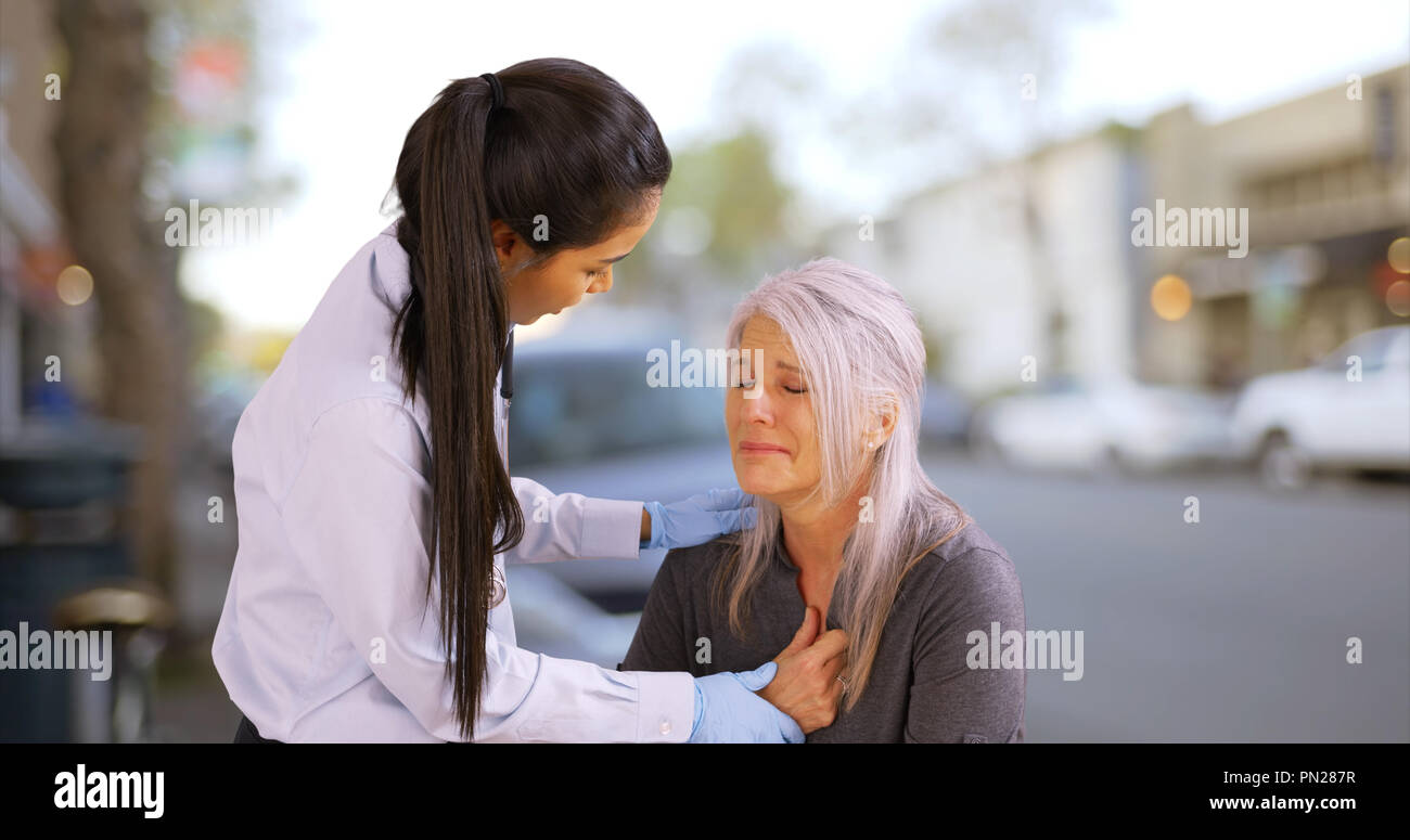 Una donna anziana ha un attacco di cuore sul marciapiede Foto Stock