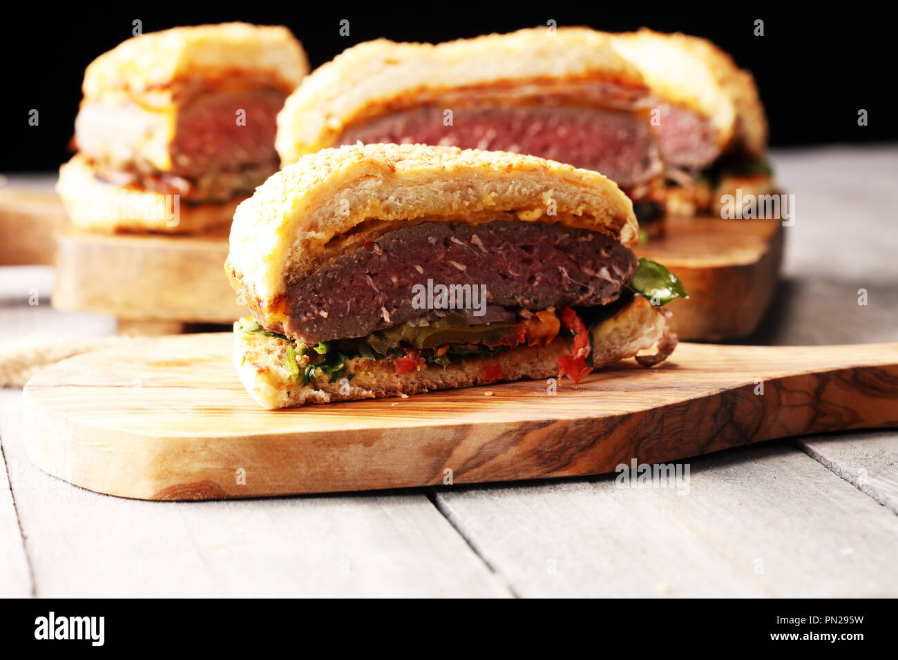 Tagliate a metà la angus burger sul cuscino di grano con il pomodoro relish, lattuga e formaggio cheddar Foto Stock