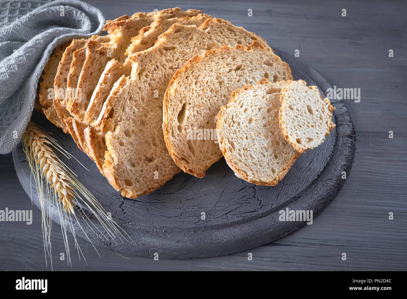Bianco Slliced pane tondo con spighe di grano su grigio rustico tavolo in legno Foto Stock