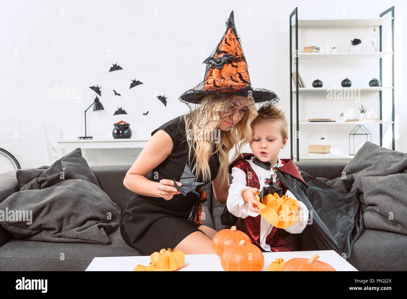 Madre e figlio in costumi di halloween con carta nera pipistrelli sul  divano di casa Foto stock - Alamy
