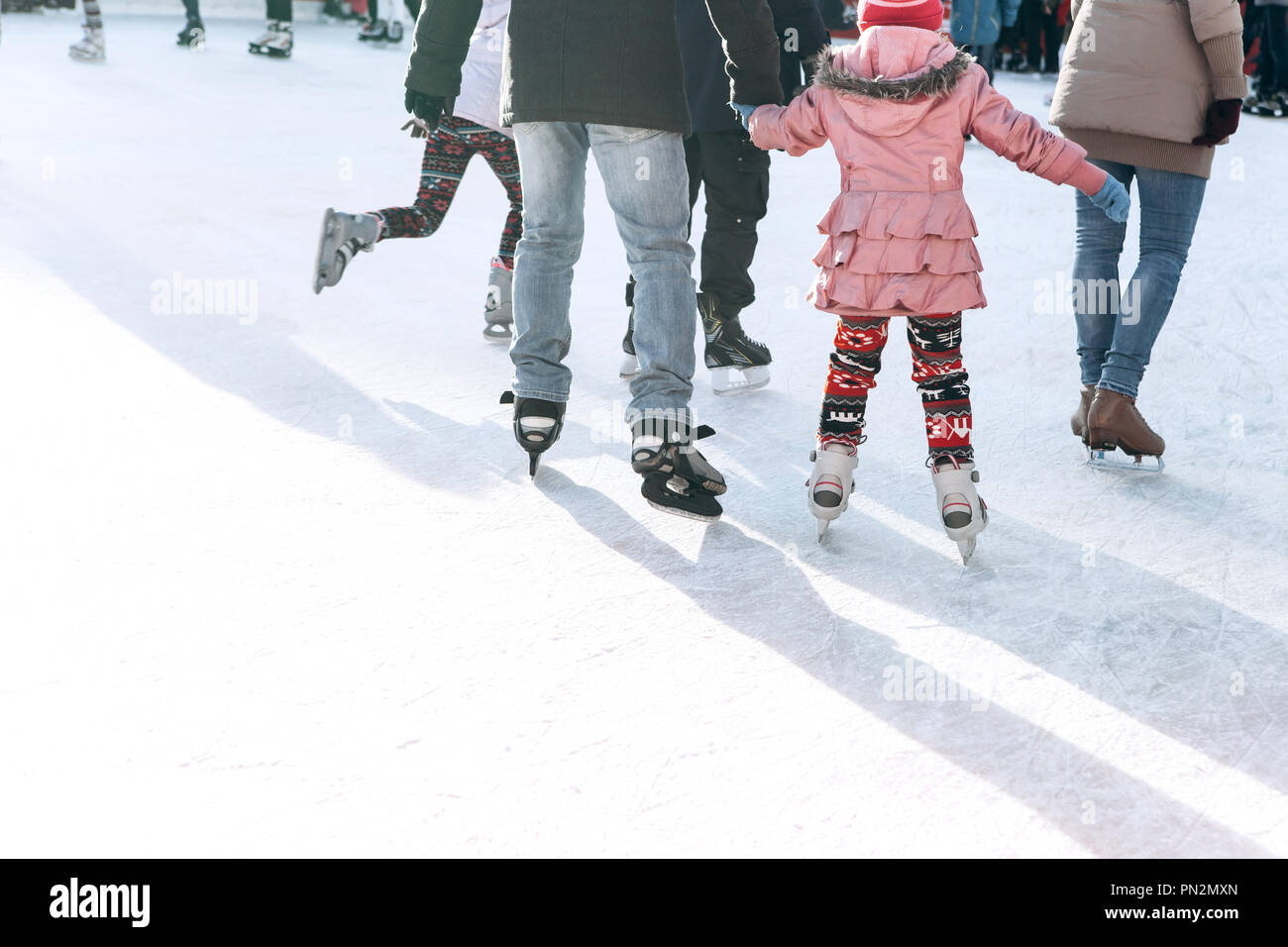 Persone corsa sulla pista di pattinaggio sul ghiaccio durante le vacanze di Natale. Sport e passatempo divertente. Foto Stock