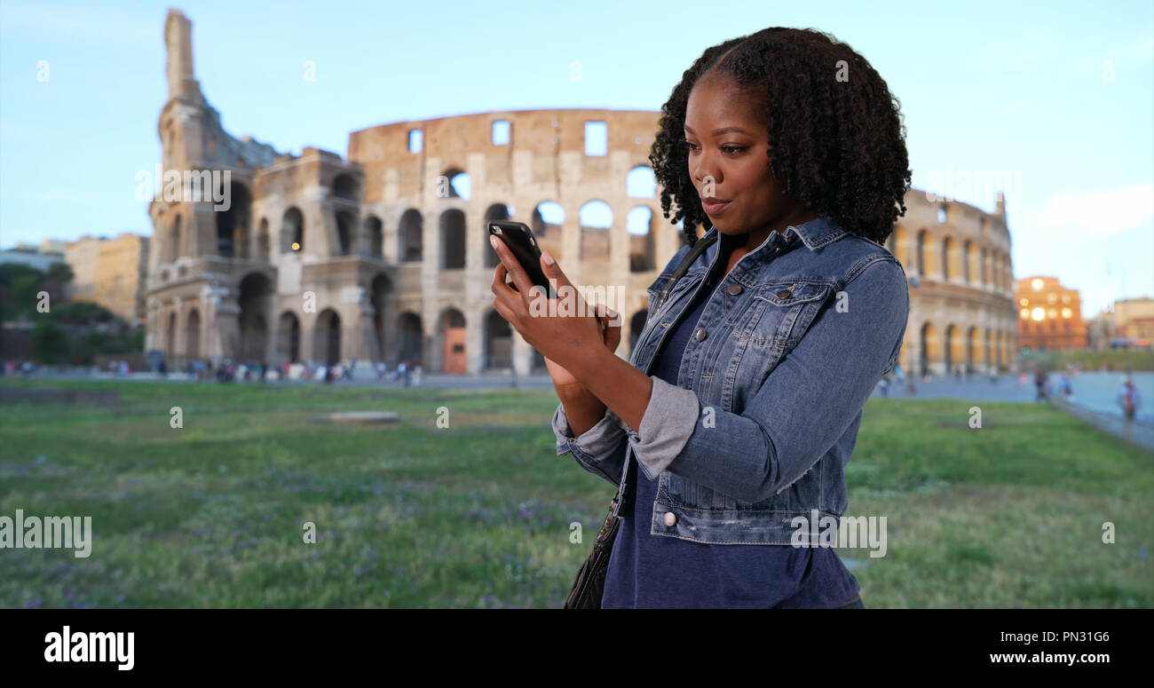 Nero donna in vacanza a Roma la lettura di un messaggio di testo da un amico da Colosseo Foto Stock