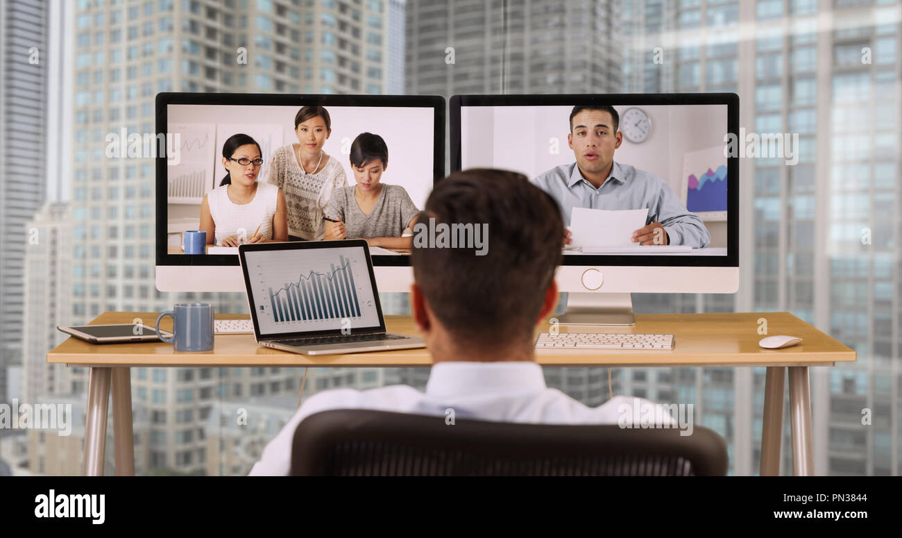 Imprenditore nel highrise office a parlare con i colleghi tramite video conferenza Foto Stock