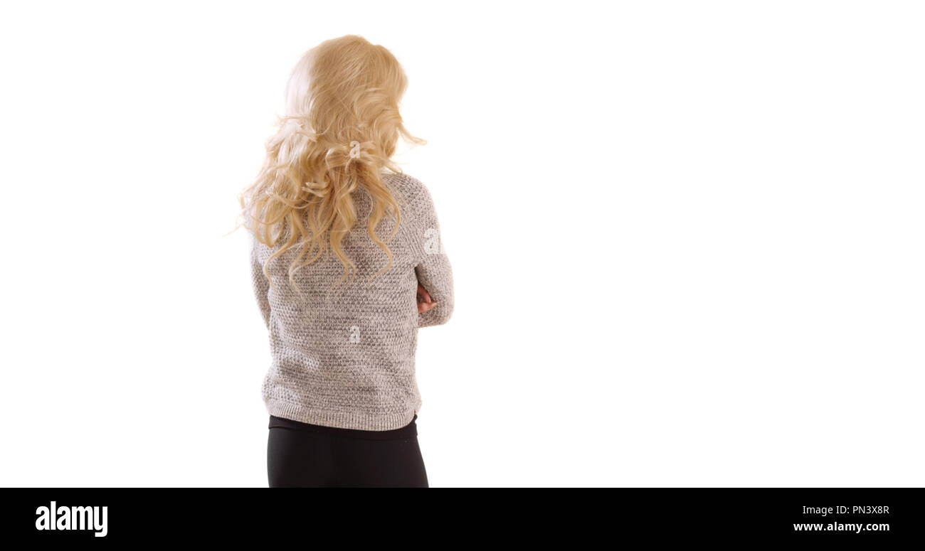Vista posteriore della donna in piedi con le braccia incrociate guardando in giro su sfondo bianco Foto Stock