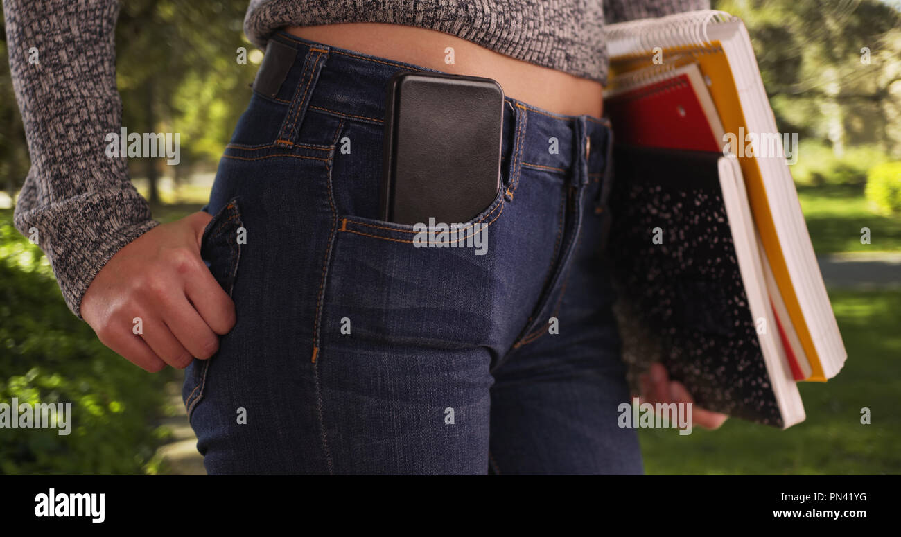Colpo stretto della sezione centrale della ragazza con un cellulare in tasca sul campus universitario Foto Stock