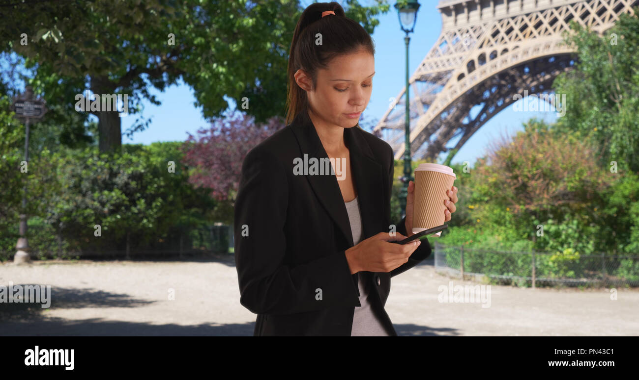 Professional donna a Parigi per un viaggio di lavoro di invio di messaggi di testo dalla Torre Eiffel Foto Stock