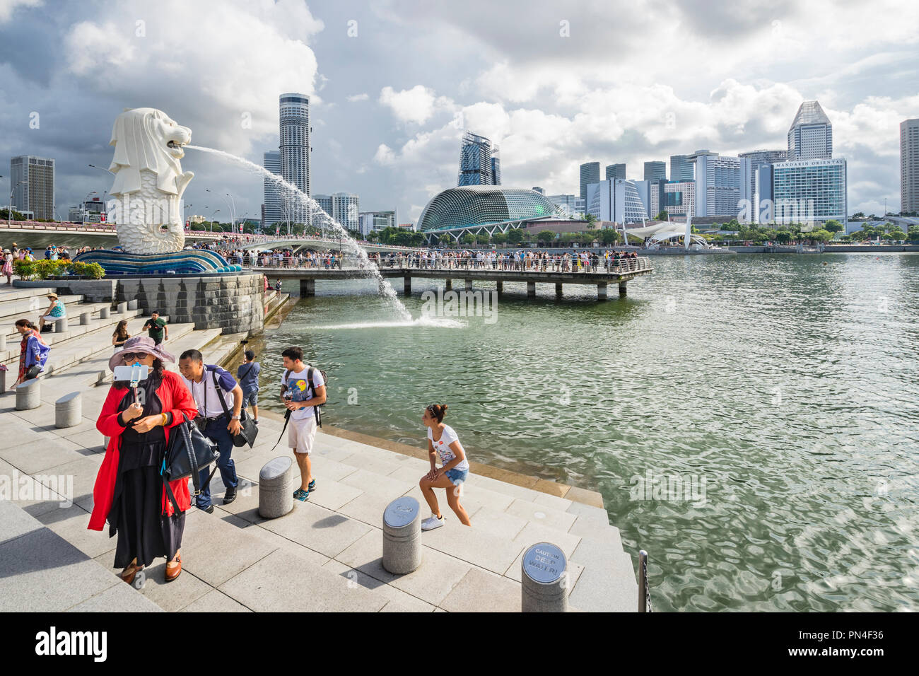 Selfie al Singapore statua Merlion, sgorga acqua in Marina Bay contro lo sfondo della Spianata i teatri sulla baia e Marina Centro Foto Stock
