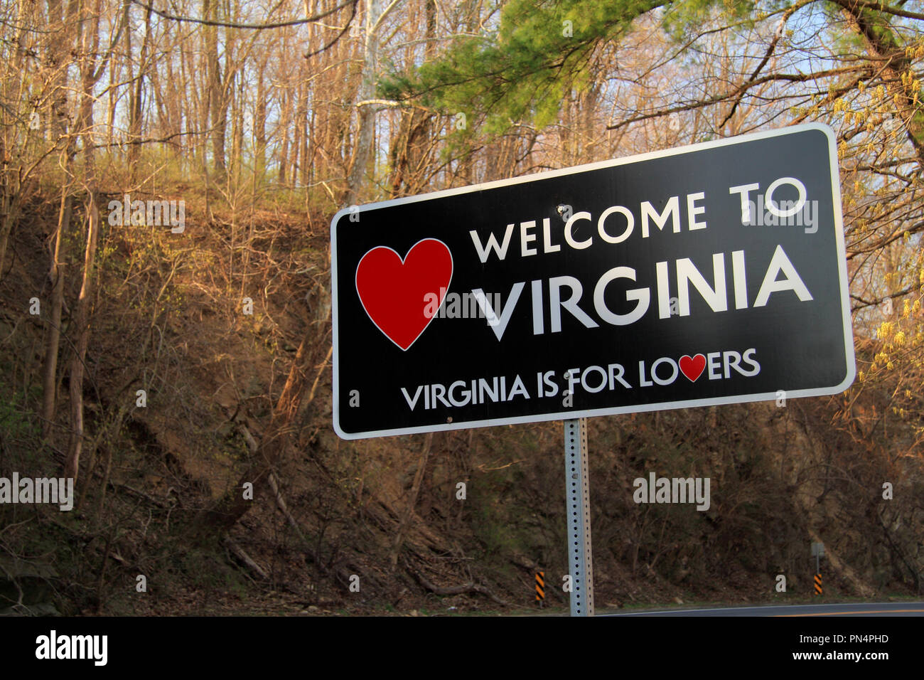 Un cartello stradale accoglie i viaggiatori lungo una strada rurale allo stato della Virginia Foto Stock