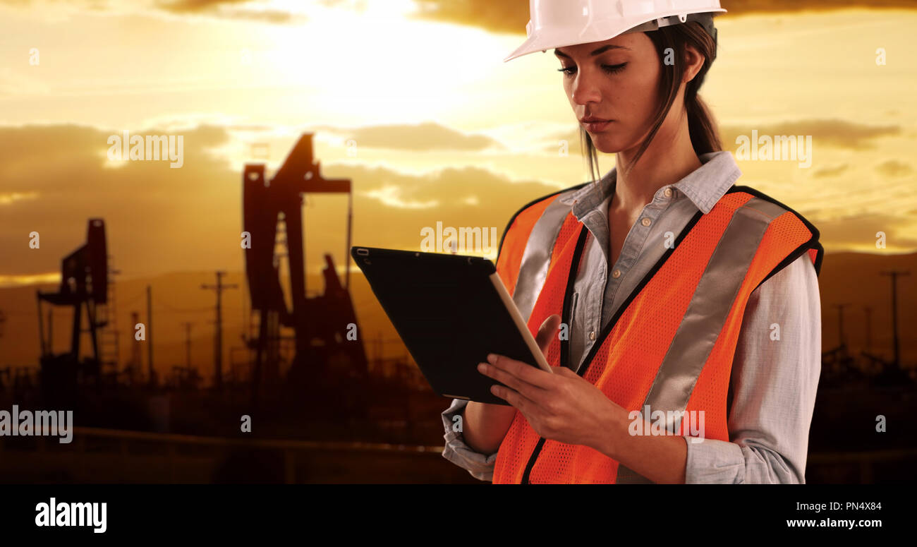 Focalizzato ingegnere femmina in un duro lavoro sul dispositivo tampone in oilfield da pumpjacks Foto Stock