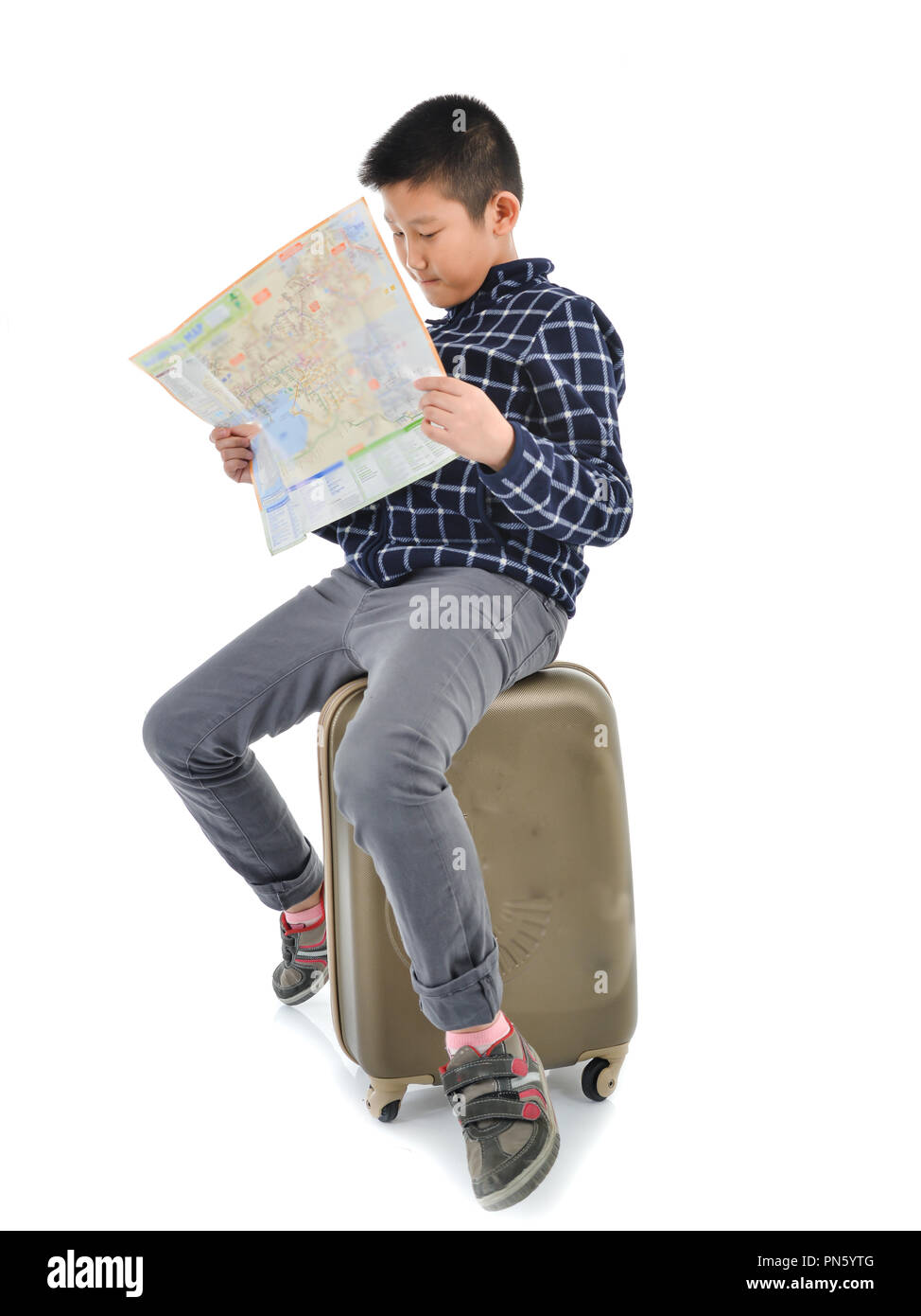 Asian ragazzo seduto su lugguage e azienda mappa su sfondo bianco. Concetto di viaggio Foto Stock