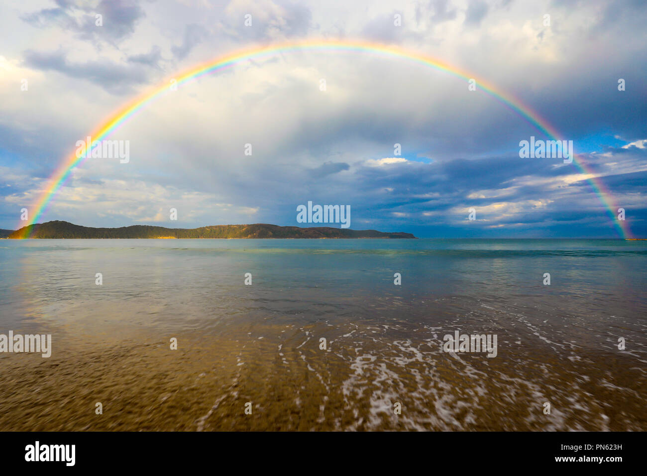 Rainbow sull'oceano e sulla spiaggia con nuvoloso cielo blu Foto Stock