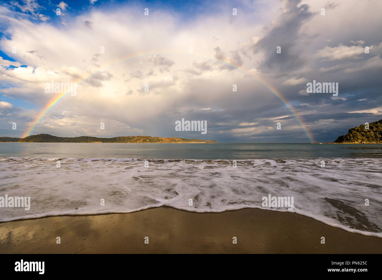 Rainbow sull'oceano e sulla spiaggia con nuvoloso cielo blu Foto Stock