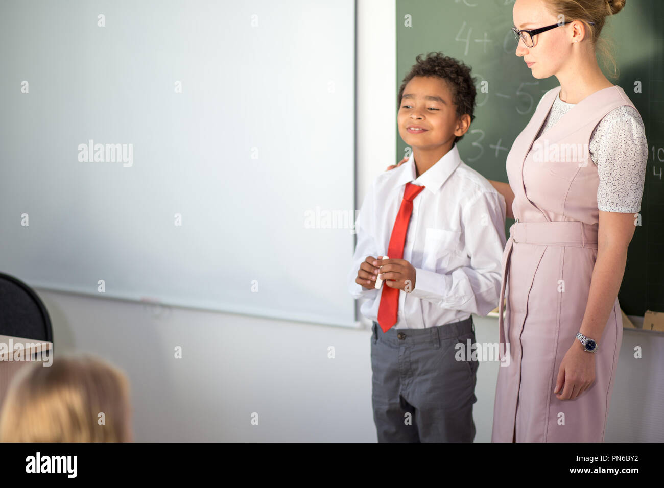 Ragazzo la risoluzione di addizione e sottrazione a bordo. scolaro iscritto soluzione di operazione matematica Foto Stock