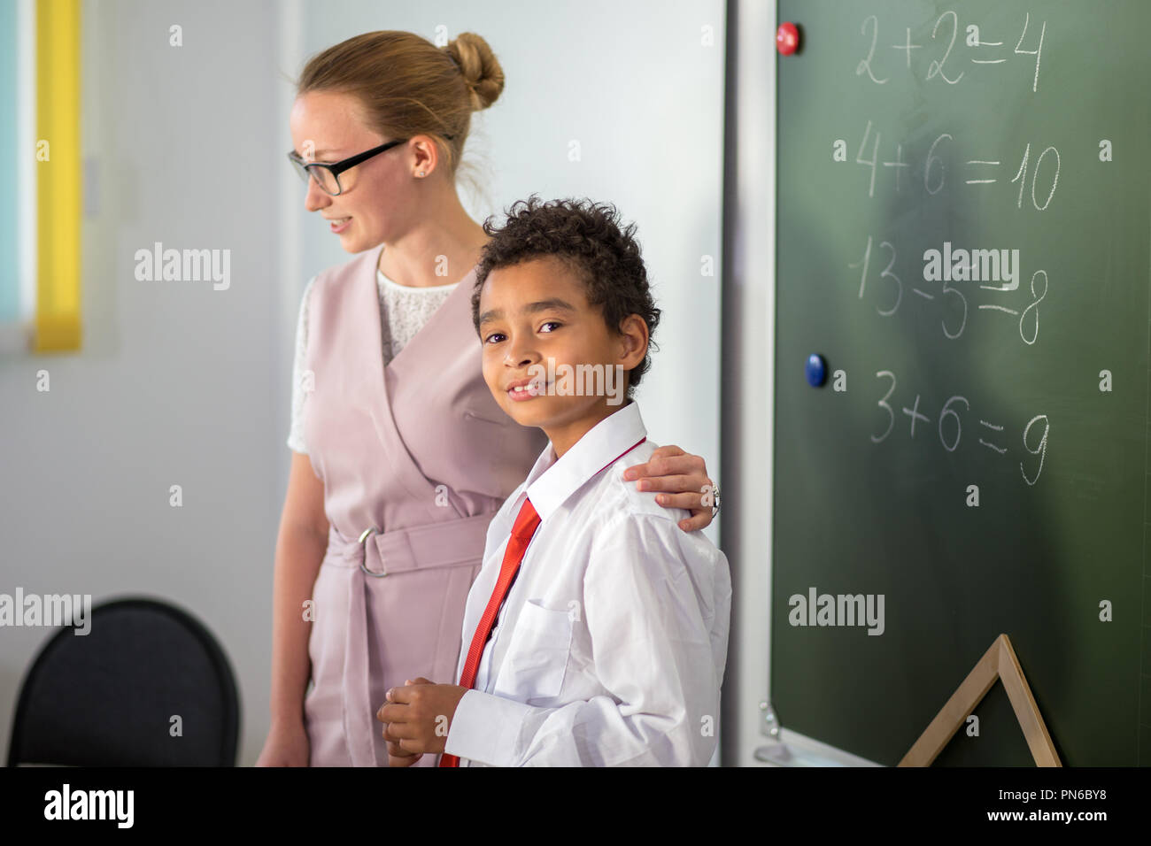Ragazzo la risoluzione di addizione e sottrazione a bordo. scolaro iscritto soluzione di operazione matematica Foto Stock