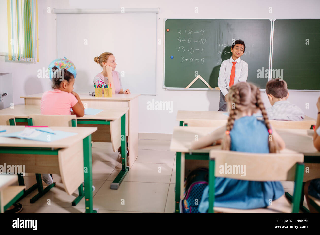 Ragazzo la risoluzione di addizione e sottrazione a bordo. scolaro iscritto soluzione di operazione matematica Foto Stock