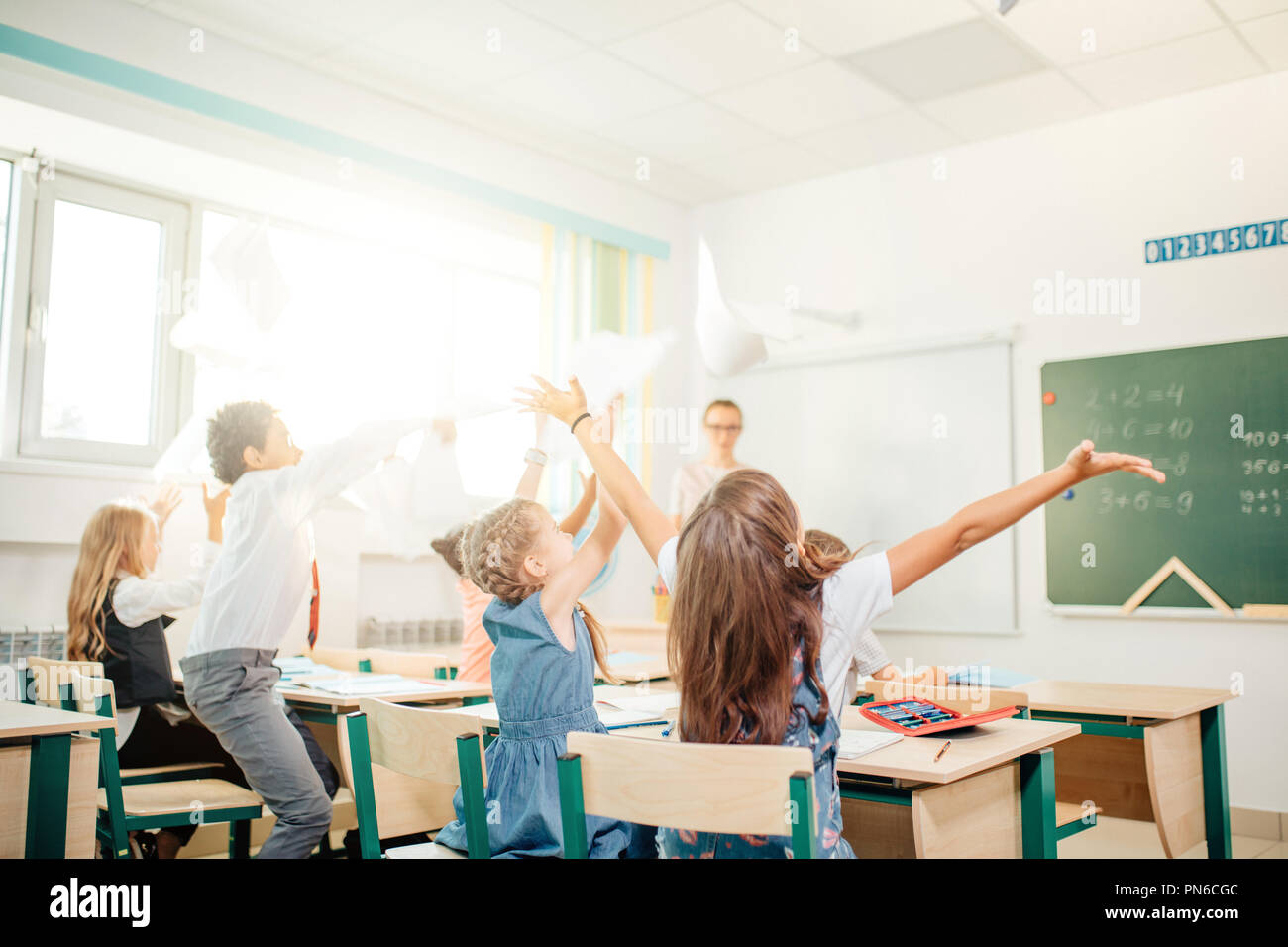 A scuola i bambini si divertono in classe e di gettare la carta in aria Foto Stock