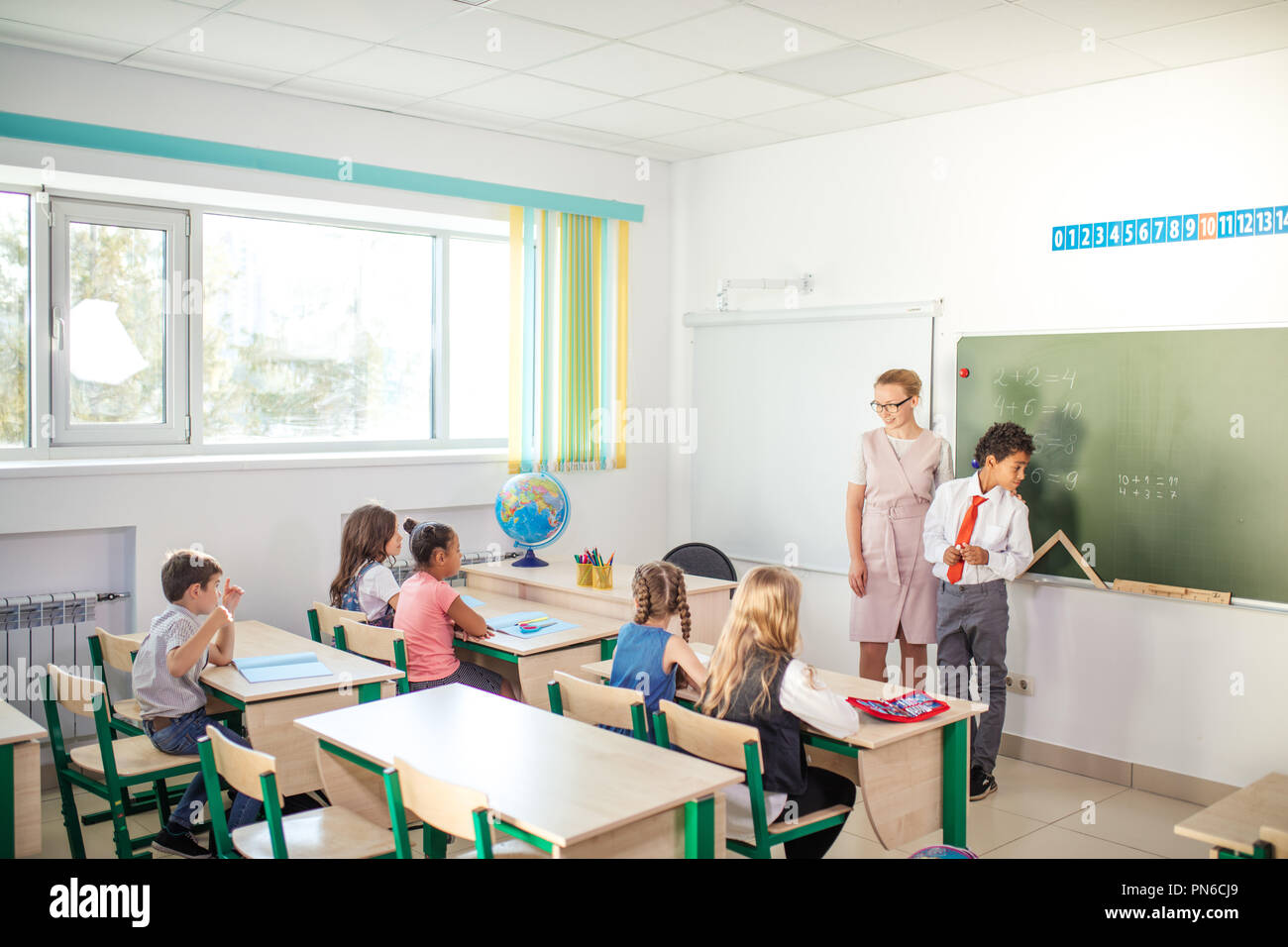 Ragazzo la risoluzione di addizione e sottrazione a bordo. scolaro iscritto soluzione di operazione matematica Foto Stock