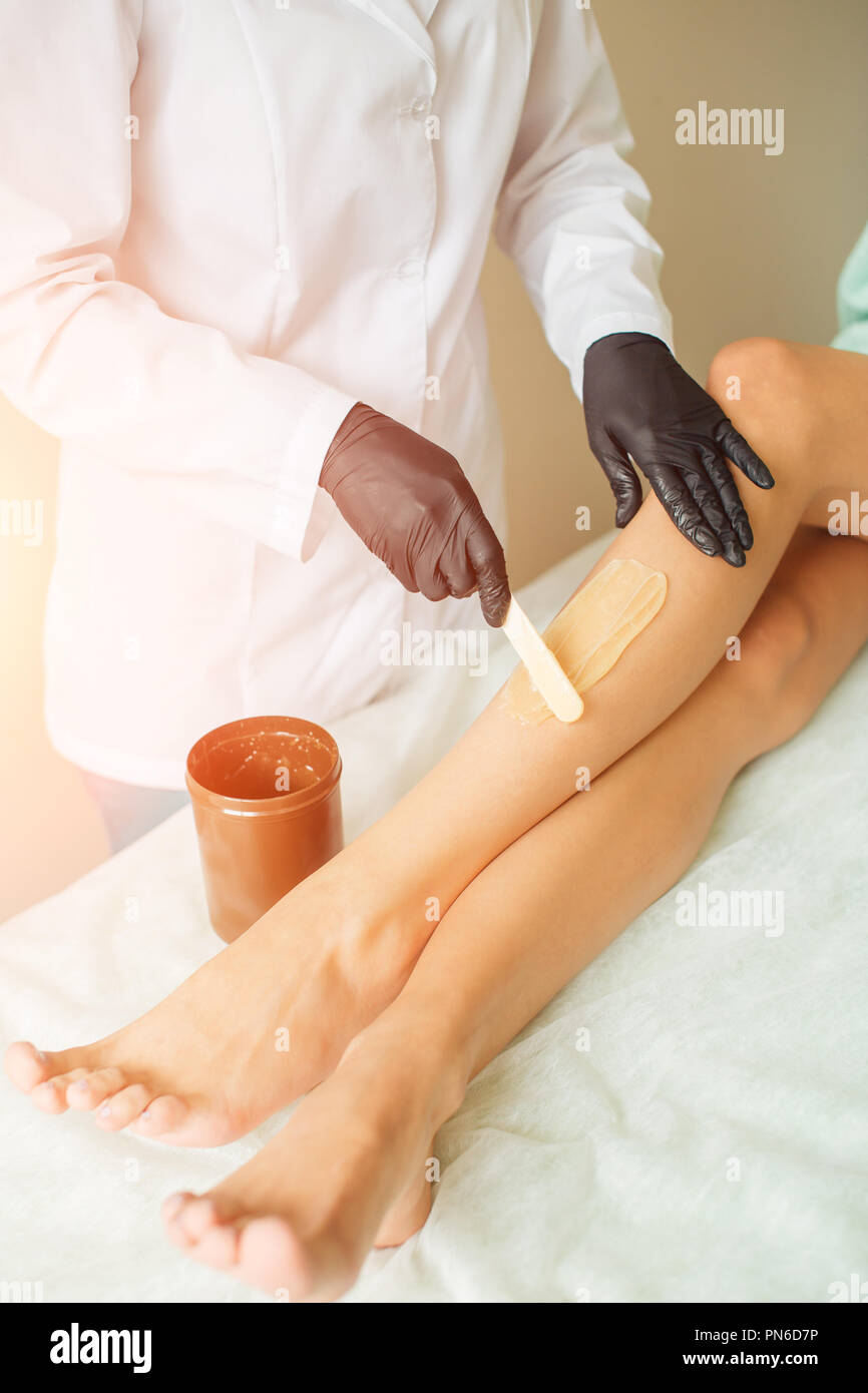 Close up estetista ceretta gambe femmina nel centro spa Foto Stock