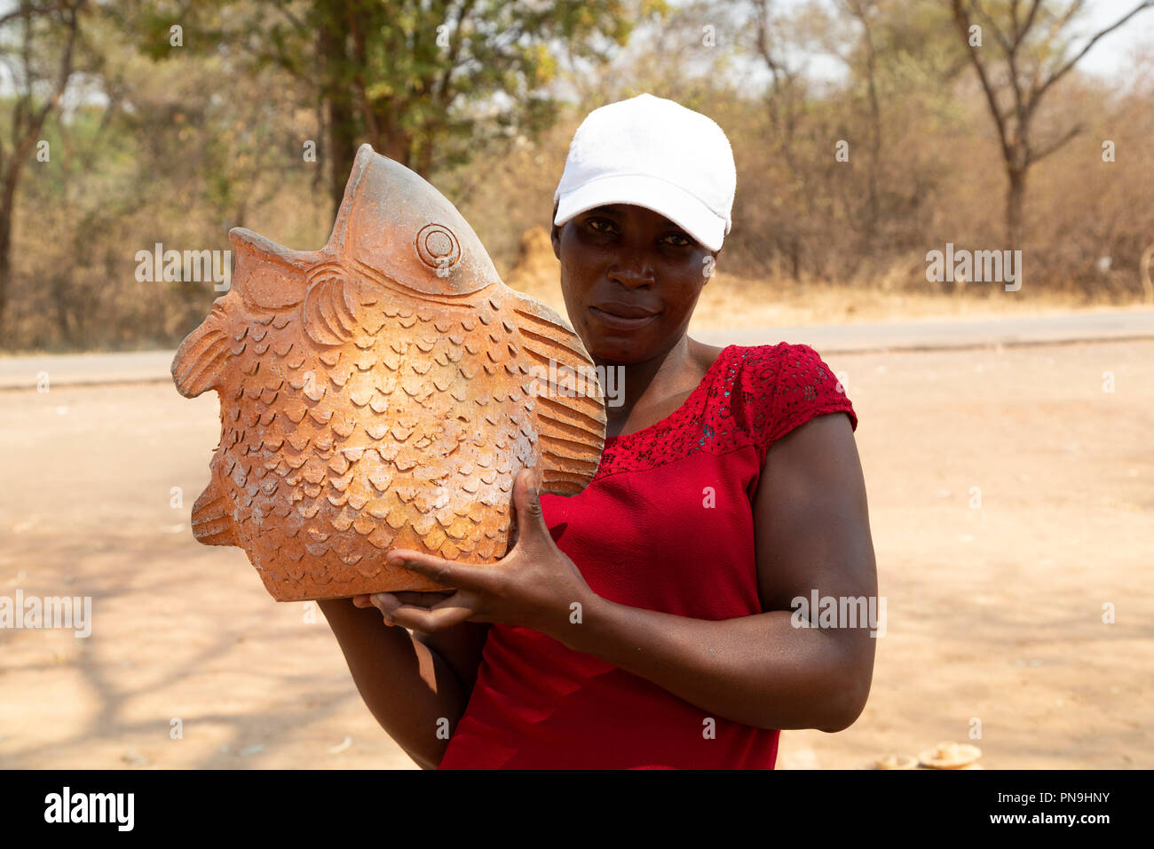 Una donna visualizza ceramica presso una strada stallo in Zimbabwe. Il pezzo è nella forma di un pesce. Foto Stock
