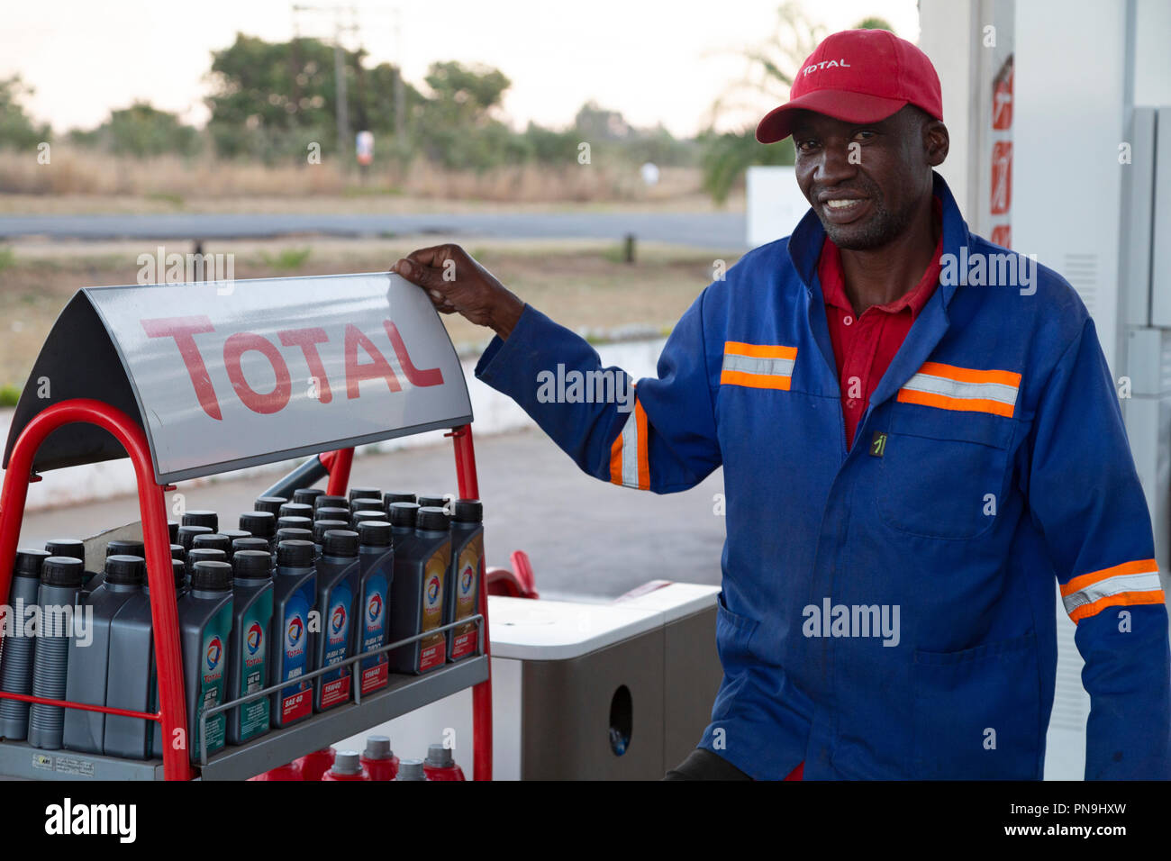 Il meccanico in un garage a est dello Zimbabwe. L uomo indossa un cappello e tute blu. Foto Stock
