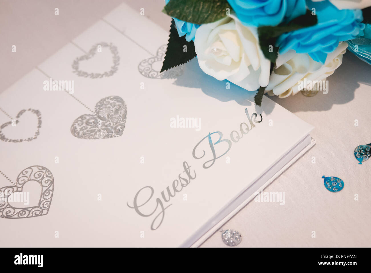 Wedding guest book prevista su bianco seta e circondato da petali di fiori Foto Stock
