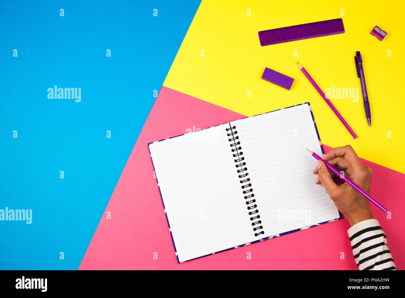 La donna la scrittura a mano in notebook su sfondo colorato Foto Stock