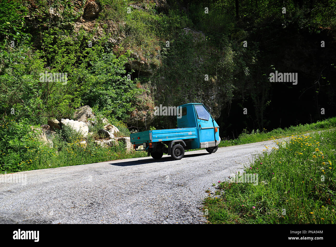 La tipica italiana a tre ruote auto, Piaggio Ape, durante la marcia in salita in Cinque Terre, Italia. Queste vetture sono utili in strette, ripide stradine del villaggio di esso Foto Stock