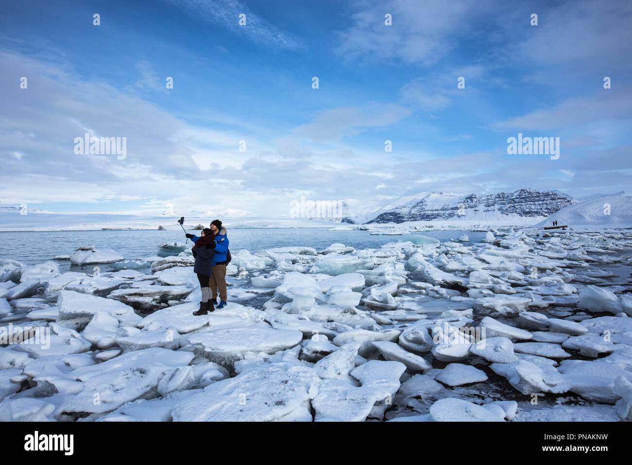 I turisti tenendo selfie fotografia utilizza lo smartphone per le foto delle vacanze a Jokulsarlon laguna glaciale, Vatnajokull National Park, Sud Est Islanda Foto Stock