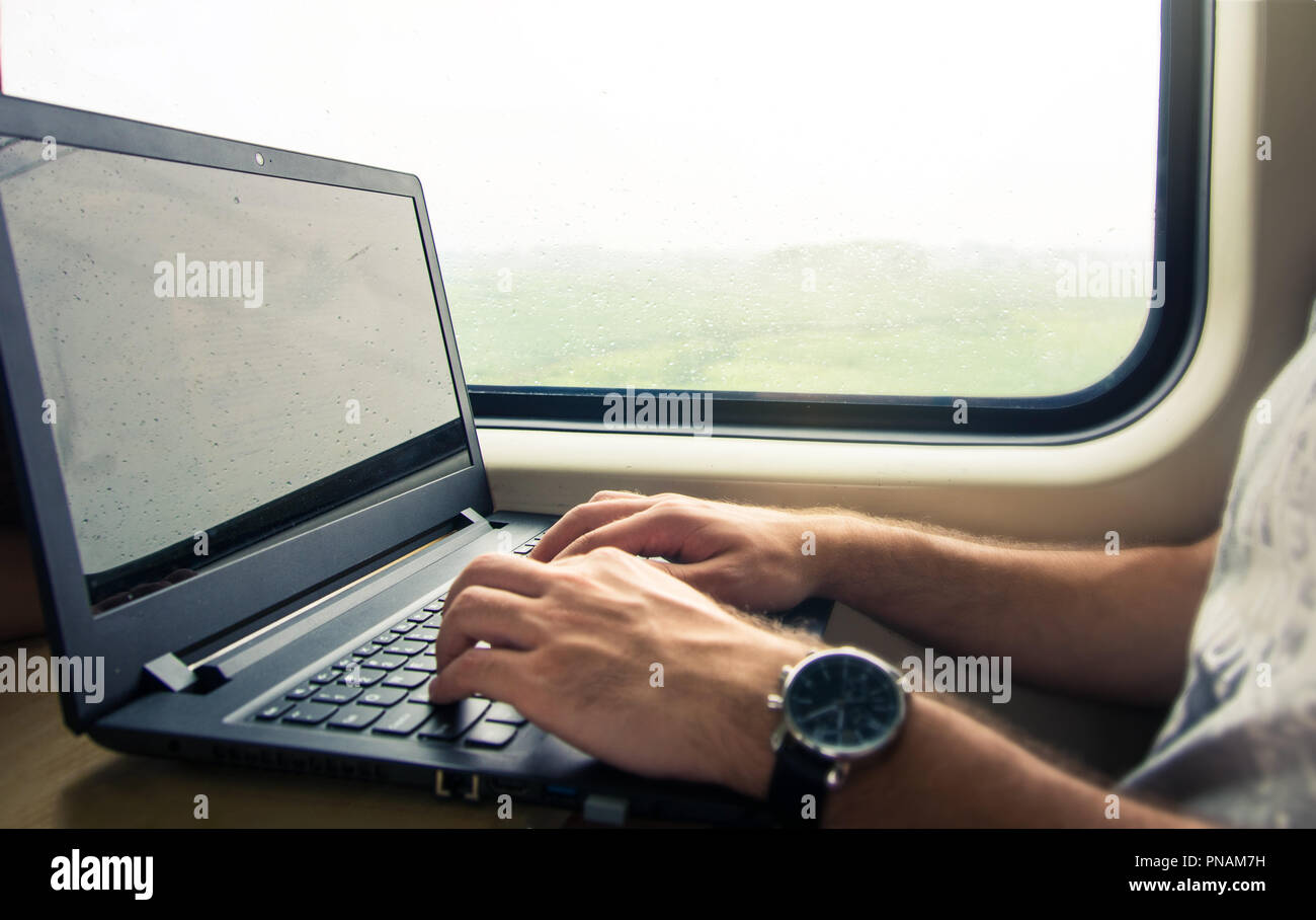 Uomo al lavoro su computer portatile in un treno Foto Stock