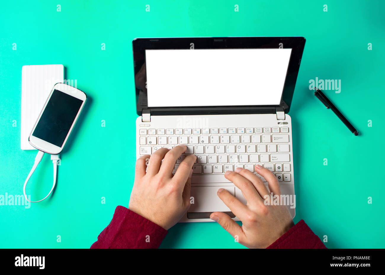 Maschio di digitazione su un bianco lap top sul tavolo blu Foto Stock