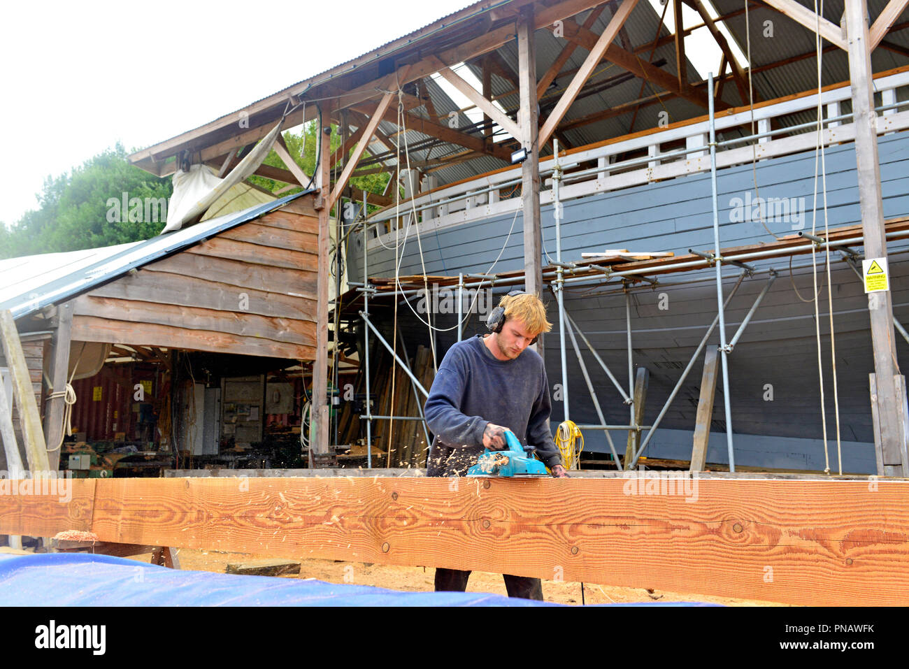 Ned Rolf (figlio di Peter Rolf boat builder)utilizzando un moderno piano di alimentazione al vero fino a 45 ft venduto braccio principale per convertire il montante da quadrato a rotondo, Truro Foto Stock