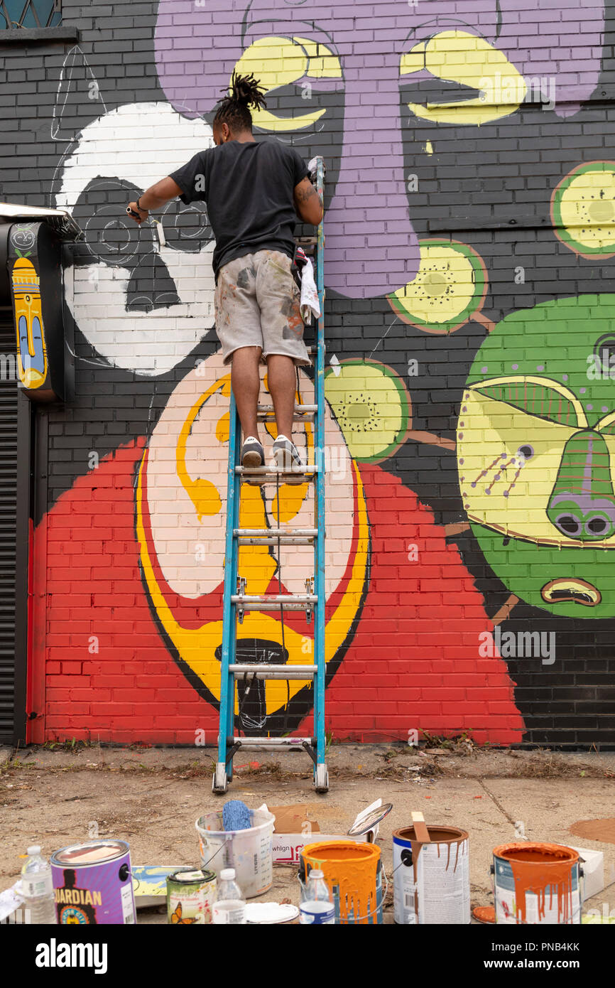 Detroit, Michigan - Tony Whlgn dipinge una parete durante il murales annuale nel mercato public art festival di Detroit orientale del quartiere del mercato. Foto Stock