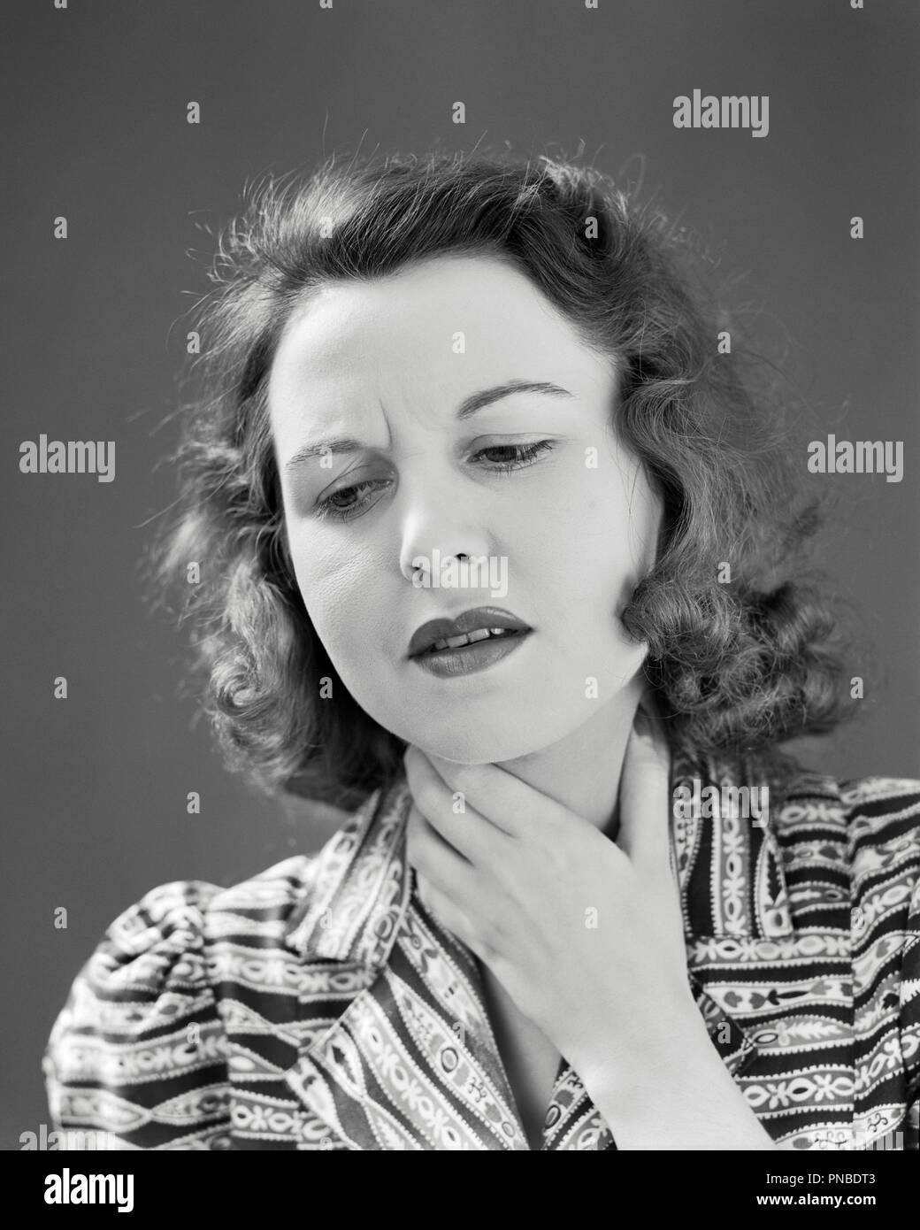 1940s donna mano al collo doloroso mal di gola - un1285 HAR001 HARS B&W TRISTEZZA BRUNETTE sofferenza testa e spalle doloroso male danneggia la vista panoramica le cattive condizioni di salute malata miserabile doloroso giovane donna adulta in bianco e nero di etnia caucasica HAR001 in vecchio stile Foto Stock