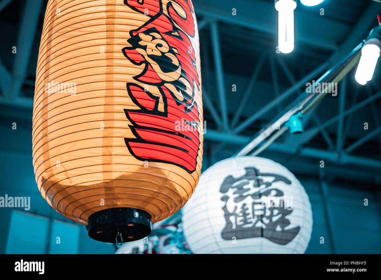 Giallo e bianco, cinese lanterne di carta, hangin dal soffitto industriali durante il commercio fashion show per le vendite autunnali. Foto Stock