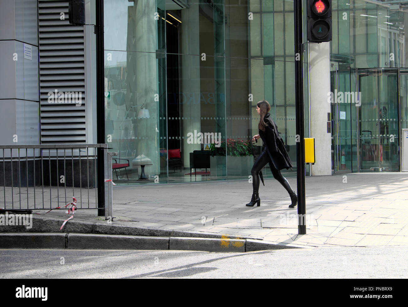 Elegante giovane donna vestita di nero a piedi lungo Finsbury Pavement al di fuori di un edificio aziendale nella città di Londra Foto Stock