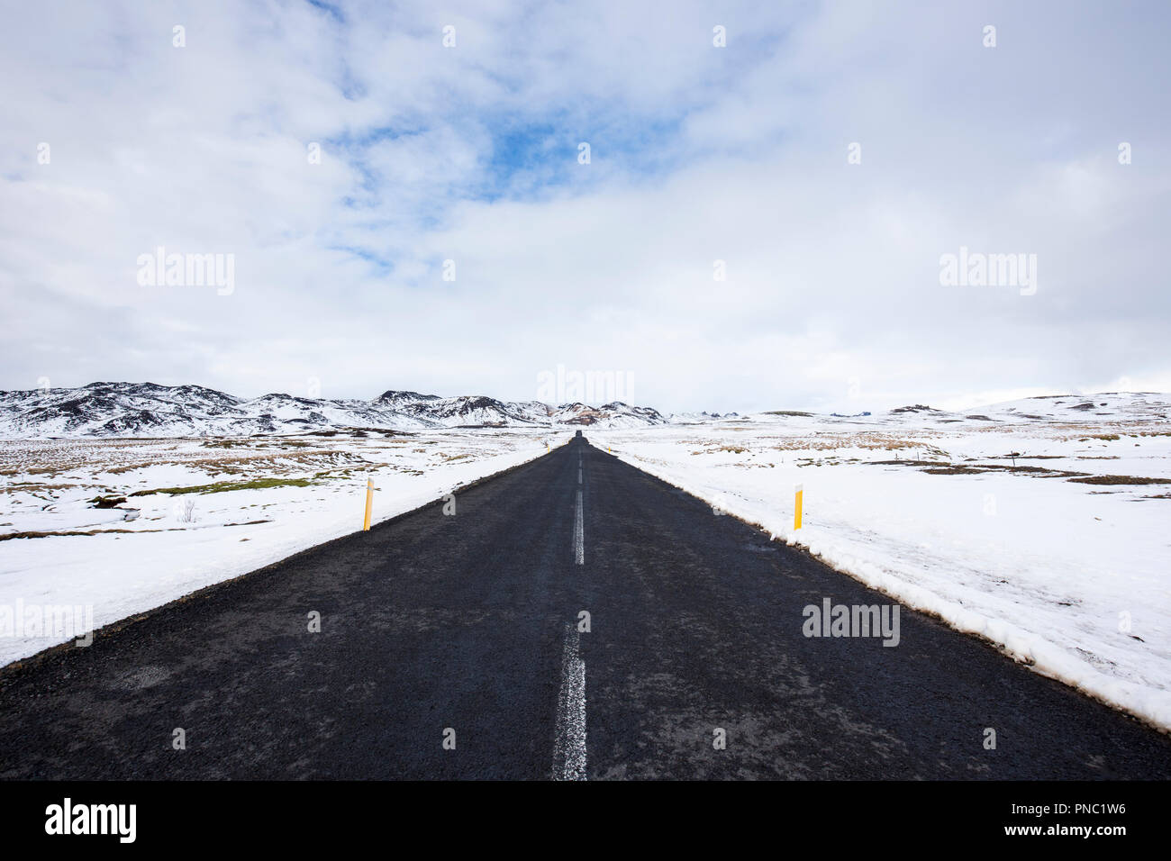La principale strada asfaltata rotta da e per Reykjavik anche se i campi di lava nel sud dell'Islanda con altezza neve marcatori sul ciglio della strada. Foto Stock