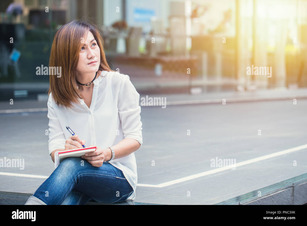 Donne asiatiche woking a mano per esterni con penna scrittura della nota. Pensando business azione di progetto. Foto Stock