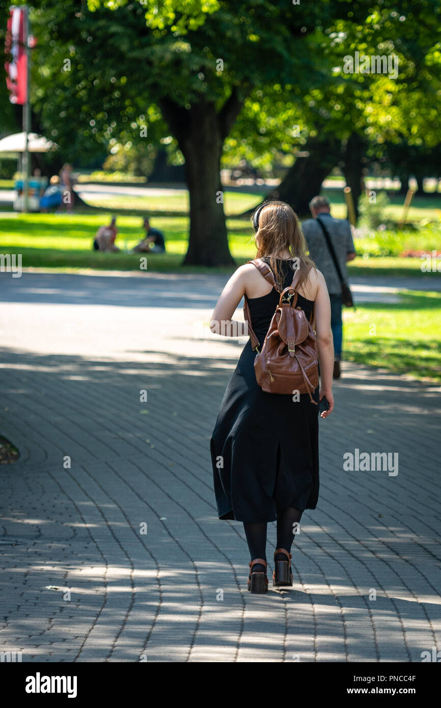 Ragazza con uno zaino camminando lungo il parco della città. Foto Stock