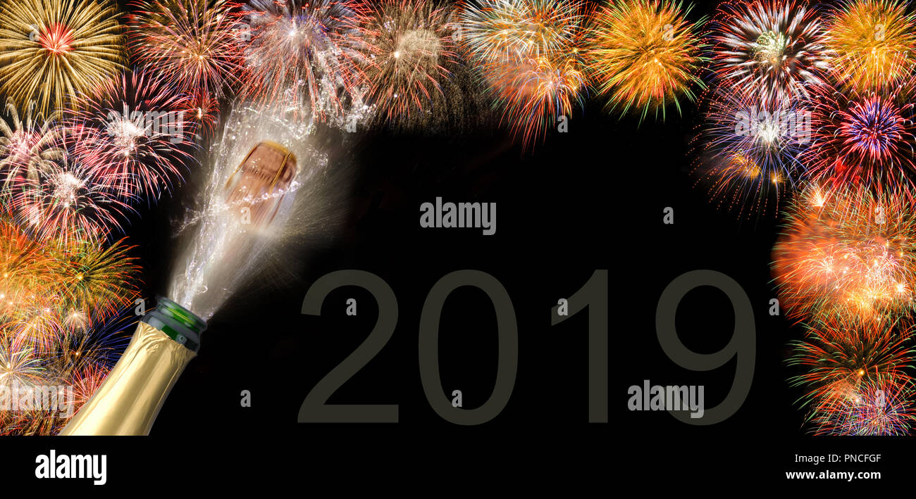 Gli spruzzi di una bottiglia di champagne con battenti sughero e fuochi d'artificio a Silvestro 2019 Foto Stock
