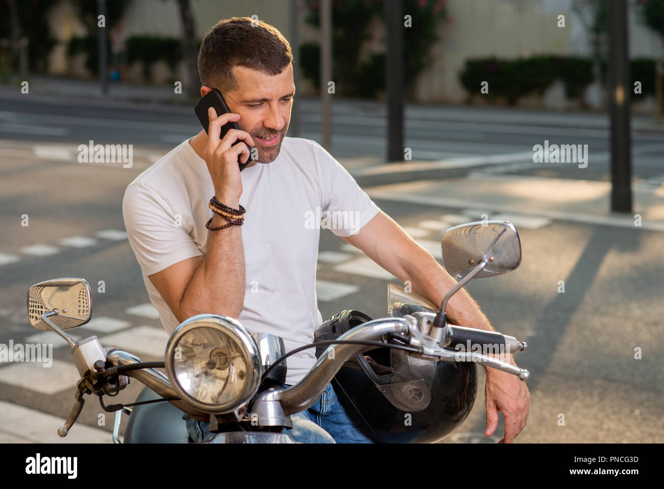 Uomo con gli scooter parla al telefono sulla città Foto Stock
