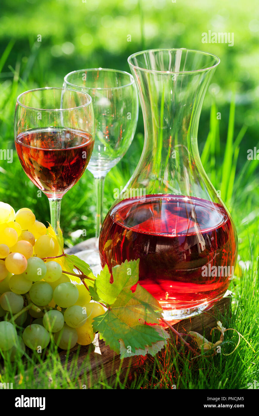Vino rosato nel decanter e bicchieri e uva. Outdoor in vigna Foto Stock