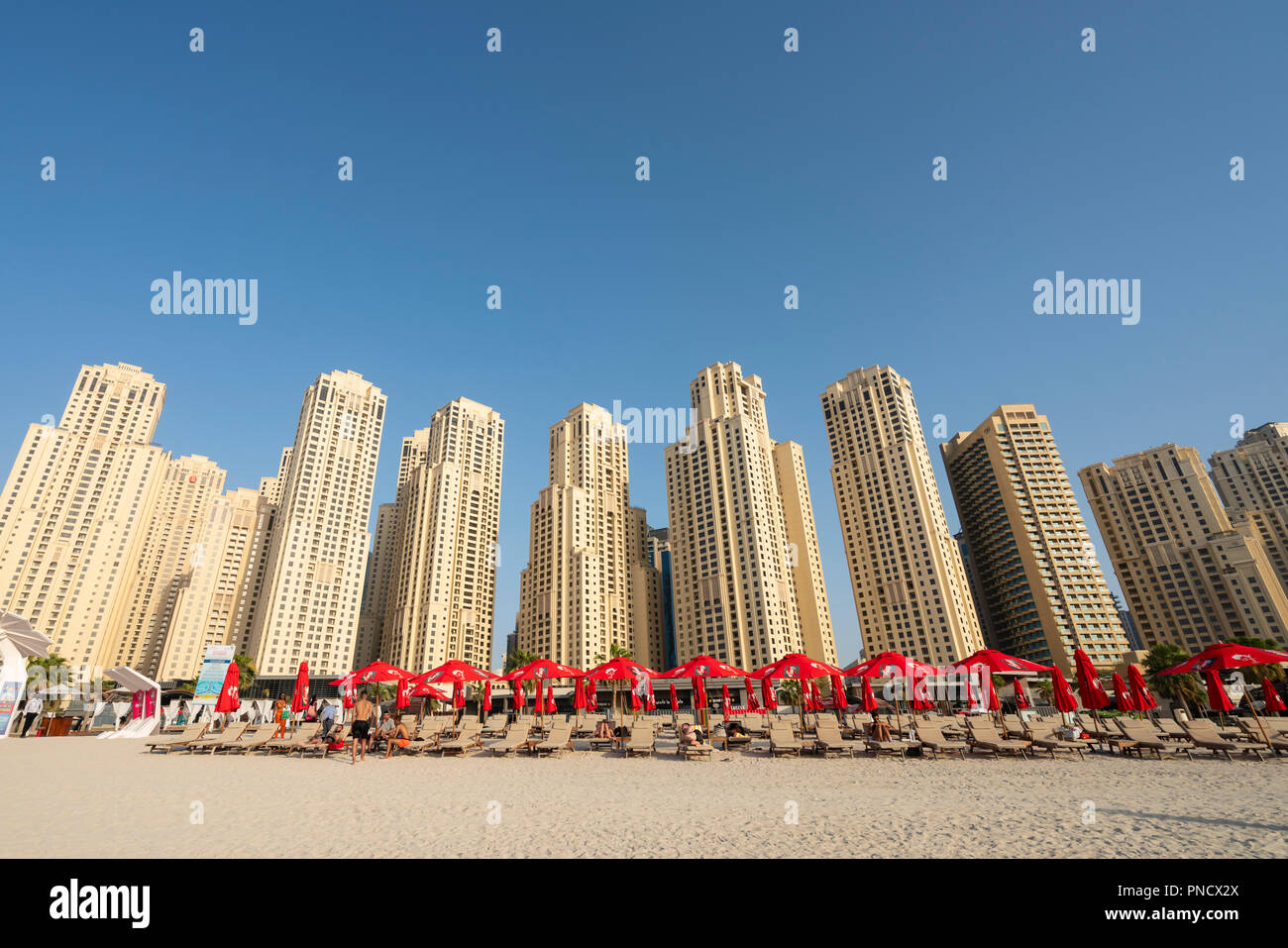 Vista della spiaggia e alto edificio di appartamenti presso la spiaggia di Jumeirah Beach distretto della moderna Dubai, Emirati Arabi Uniti, Emirati Arabi Uniti. Foto Stock
