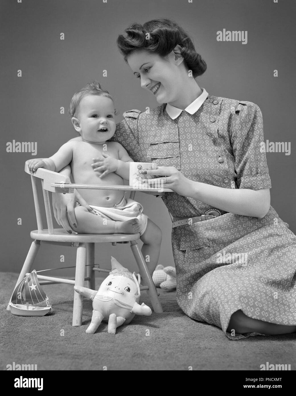 1940s sorridente madre di sostegno di uno anno vecchio figlio bambino seduto in poltrona tra vari giocattoli - b12628 HAR001 HARS stile giovanile giovane adulto equilibrio forte lieta gioia femmine LADIES FITNESS FISICO DELLE PERSONE CURA B&W felicità benessere stili allegri tra i sorrisi connessione UPDO VITTORIA rotoli gioiosa elegante vari BABY BOY personale di supporto attacco affetto emozione mode la crescita novellame mamme un anno vecchio affiatamento in giovane donna adulta in bianco e nero di etnia caucasica HAR001 in vecchio stile Foto Stock