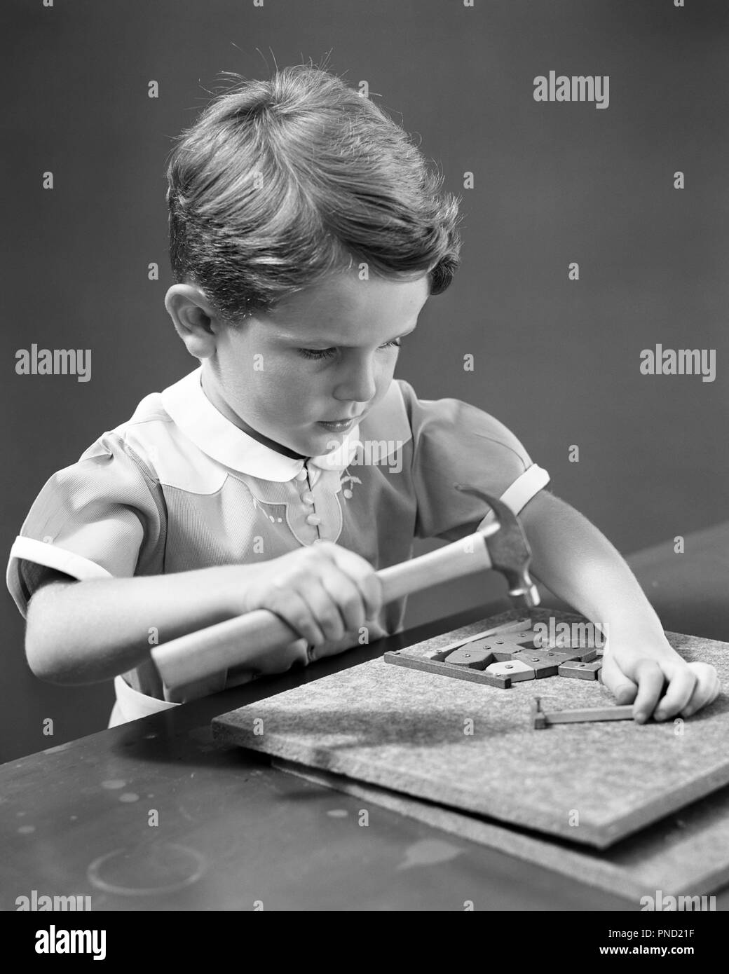 1940s intenti giovane ragazzo giocando con la costruzione della scheda di apprendimento gioco GIOCATTOLO CHE COMPORTANO L'USO DELLE MANI E UN MARTELLO E CHIODI - J1918 HAR001 HARS spazio copia di metà lunghezza chiodi maschi espressioni di fiducia B&W SUCCESSO STRATEGIA MANUALE E L'emozione del progresso della conoscenza la ricreazione di innovazione didattica di elegante concettuale DETERMINATA LA CRESCITA CHE COINVOLGONO I RAGAZZI DI PRECISIONE uso di rilassamento in bianco e nero di etnia caucasica concentrazione destrezza HAR001 intenti di vecchio stile Foto Stock