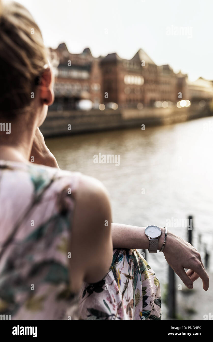 Vista posteriore della donna seduta oltre il fiume in città Foto Stock