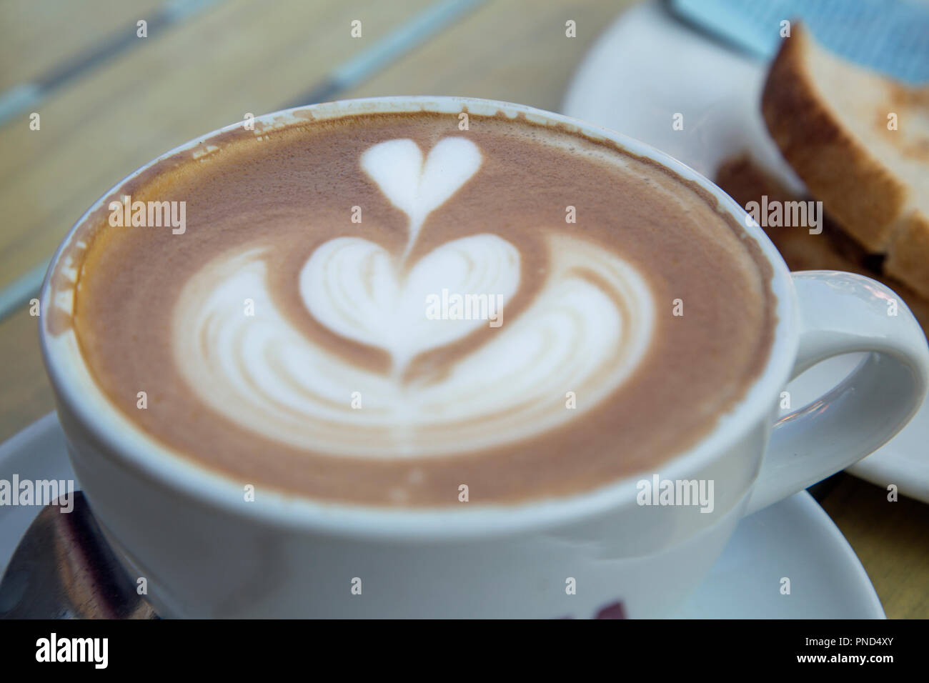 Una tazza di caffè con una decorazione a forma di cuore ad volute sulla superficie. Foto Stock