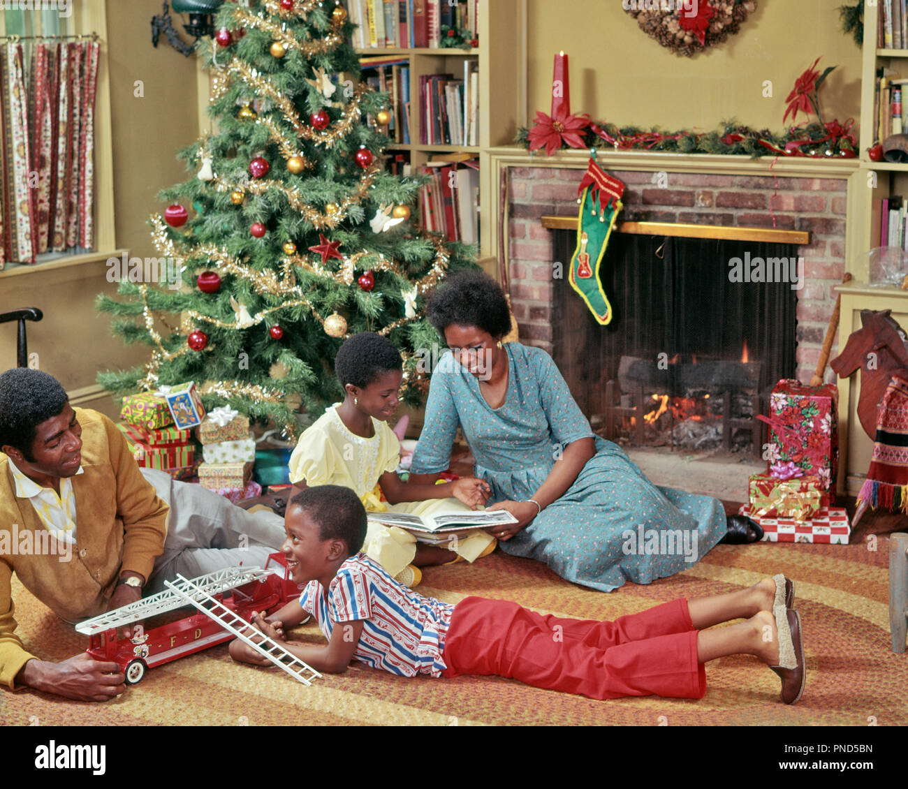 Regali Di Natale Per Giovani Coppie.Anni Settanta Famiglia Americana Africana Di Quattro Sul Soggiorno Piano Giocando Con I Giocattoli Di Natale