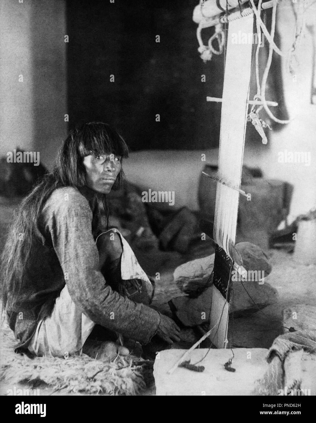 1890s 1898 Native American Indian uomo guardando la telecamera cerimoniale di tessitura KILT SUL TELAIO - Q73416 CPC001 HARS PRECISIONE Tessitura Tessitura giovane uomo adulto BANGS IN BIANCO E NERO il cerimoniale KILT TELAIO VECCHIO TESSITORE Foto Stock