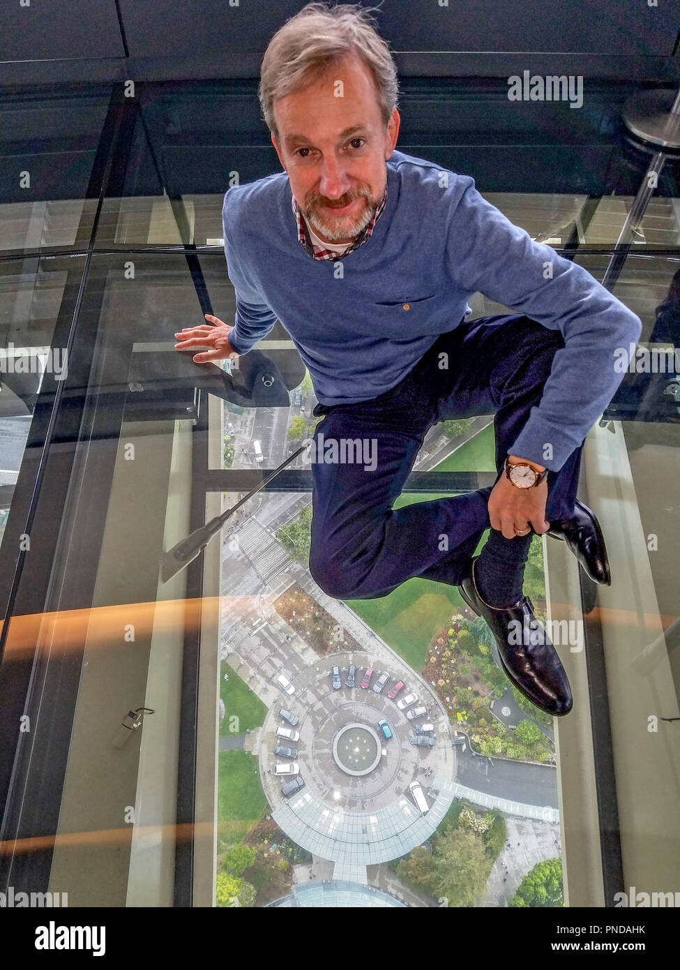 Richard Green, l' esperto di vetro", la cui società di consulenza anteriore, progettato il piano di vetro e la piattaforma di osservazione per il rinnovato lo Space Needle. Egli è seduto su un pavimento di vetro con servizio parcheggio per l'ago visto 500 piedi sotto. Foto Stock