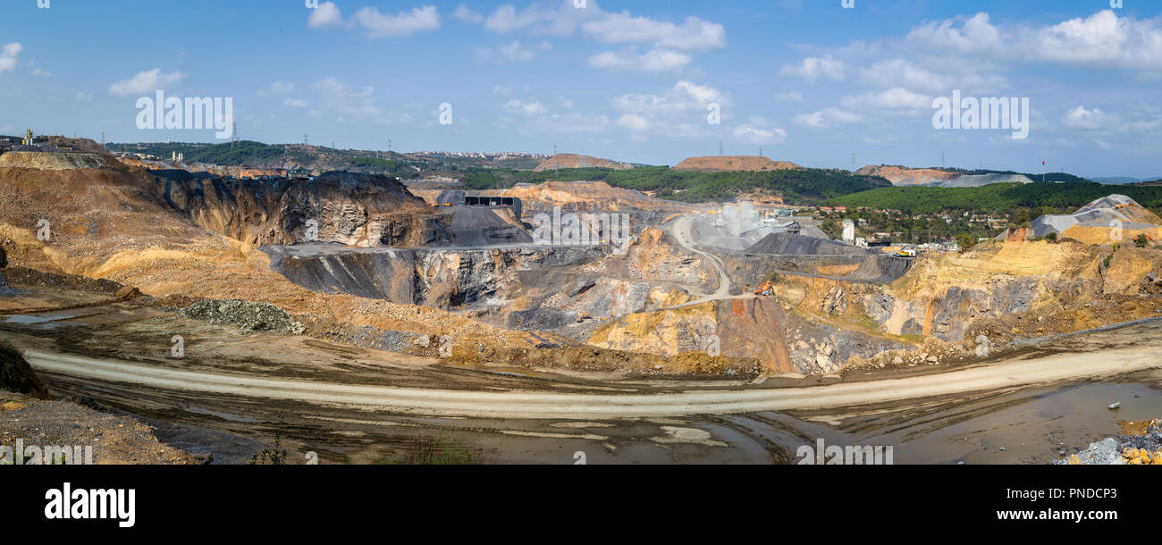 Panoramica un ampio angolo di visione di una cava. Cava è un tipo di miniera a cielo aperto in cui dimensione pietra, roccia, costruzione aggregato, riprap, sabbia e ghiaia. Foto Stock